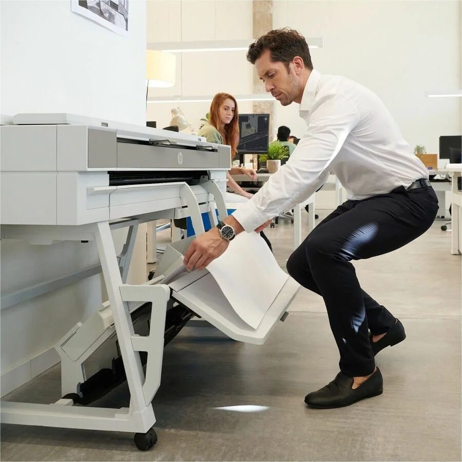 Technician loading paper during HP DesignJet Maintenance on a wide-format printer.