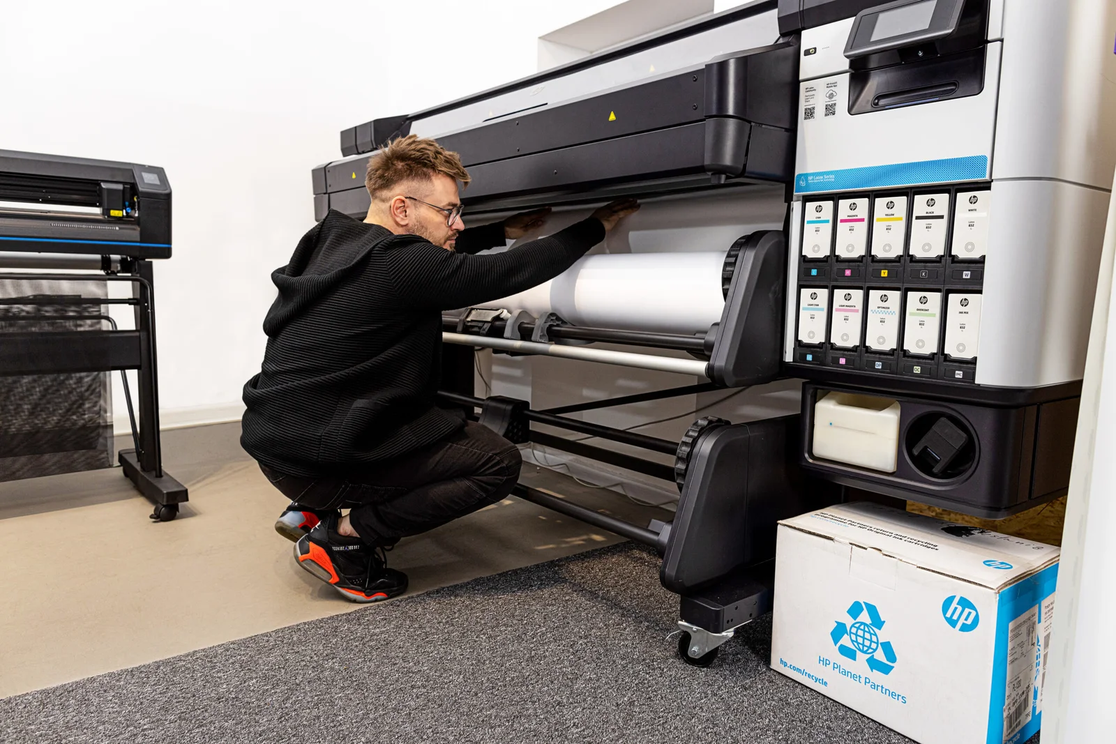 Technician checking the roll feed area during HP Latex Plotter Repair service.