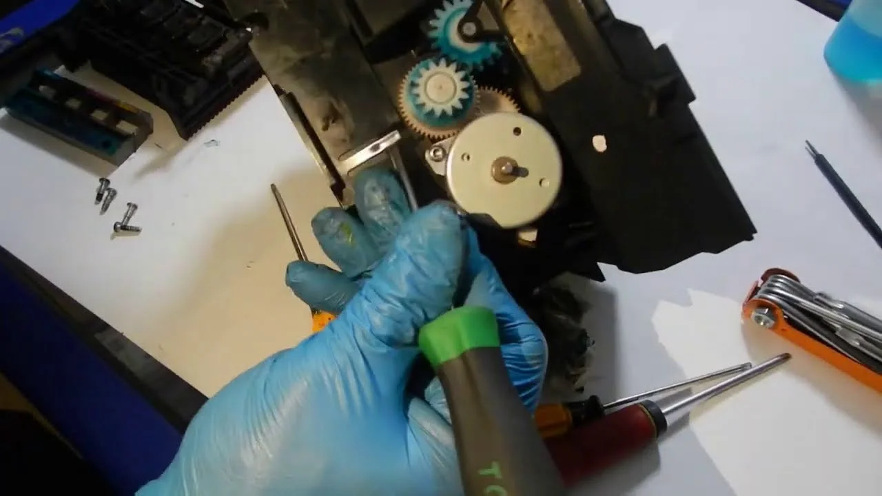 An HP Plotter Service Technician repairing internal gear components inside a plotter.